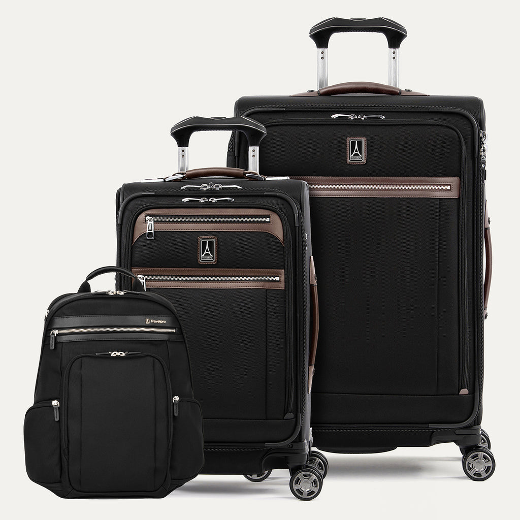 Set of black suitcases with brown accents  and a black backpack on a white background