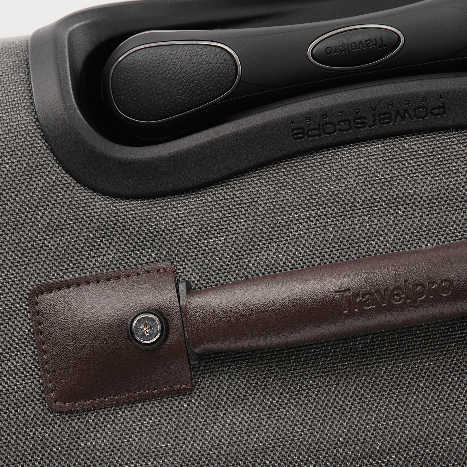 Close-up of a suitcase handle with a brown leather wrap on a gray textured suitcase.