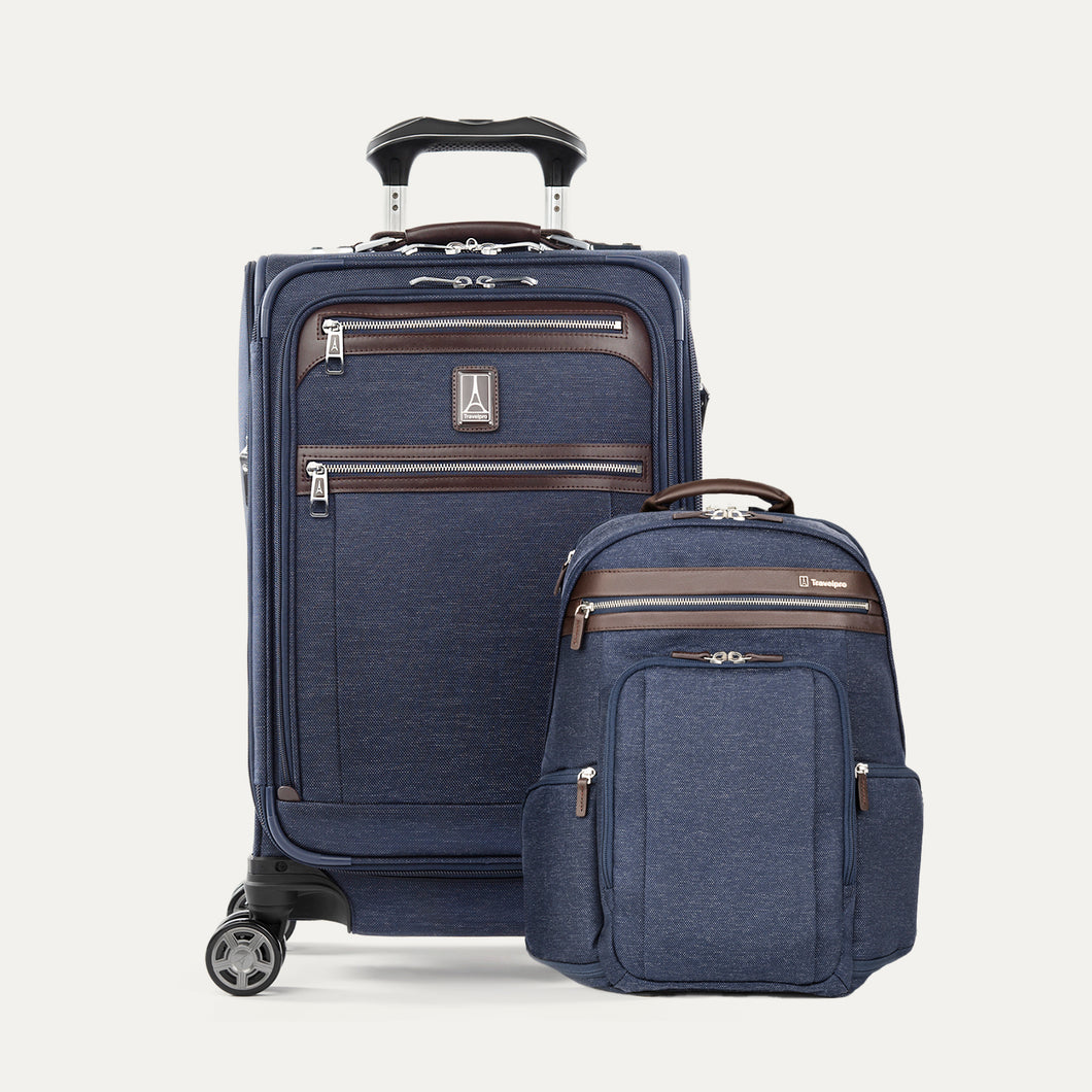 A set of travel luggage consisting of a carry-on spinner suitcase and a business backpack, both in navy blue color with brown leather accents and chrome zippers.