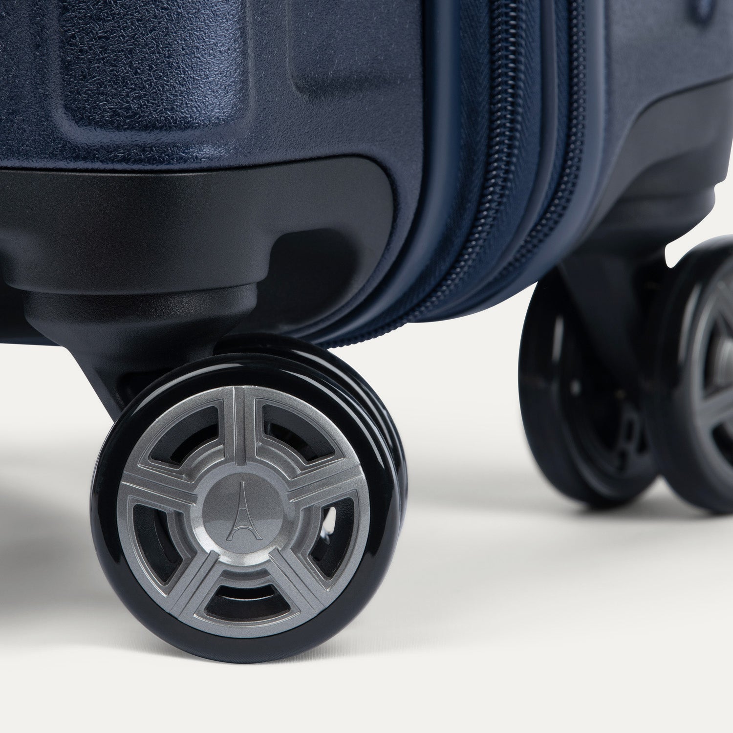 Close-up of a navy blue suitcase wheels on a white background