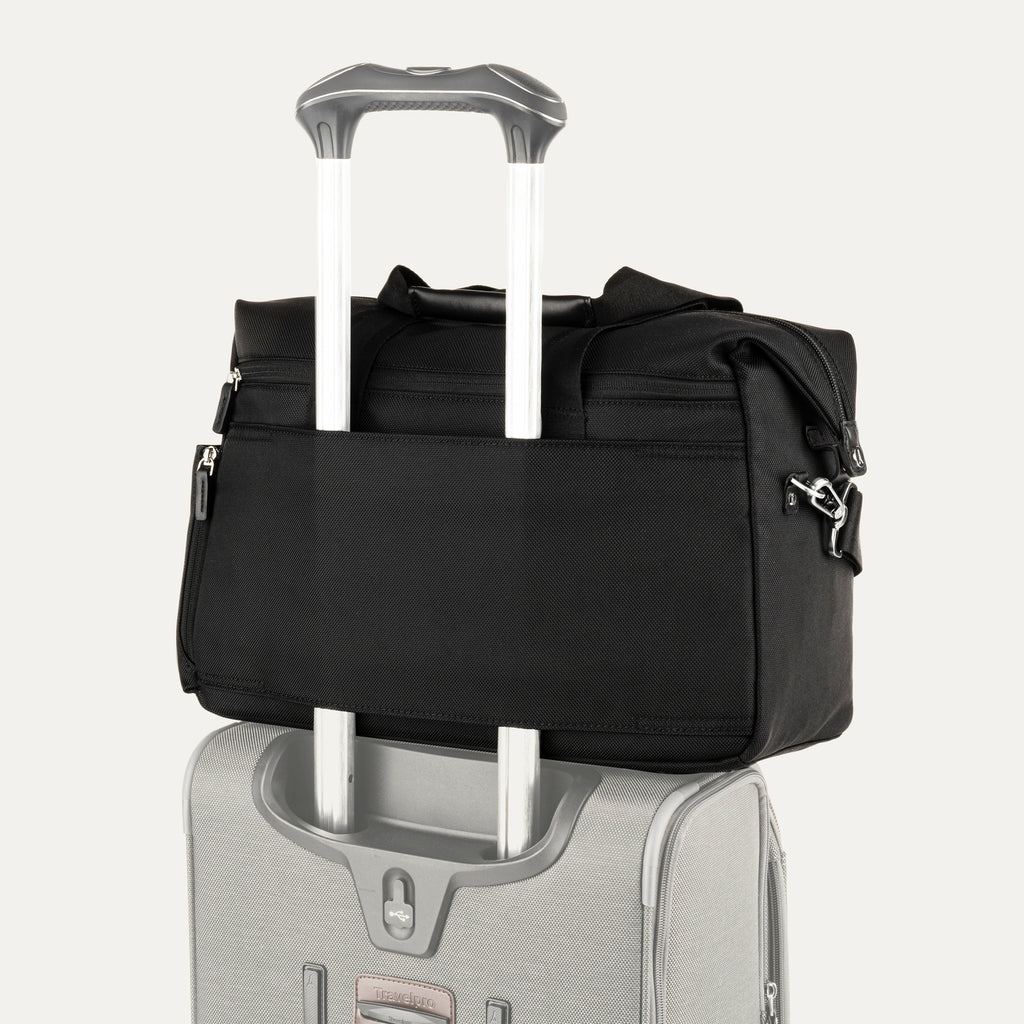Black tote secured over suitcase handle using rear strap, on a white background
