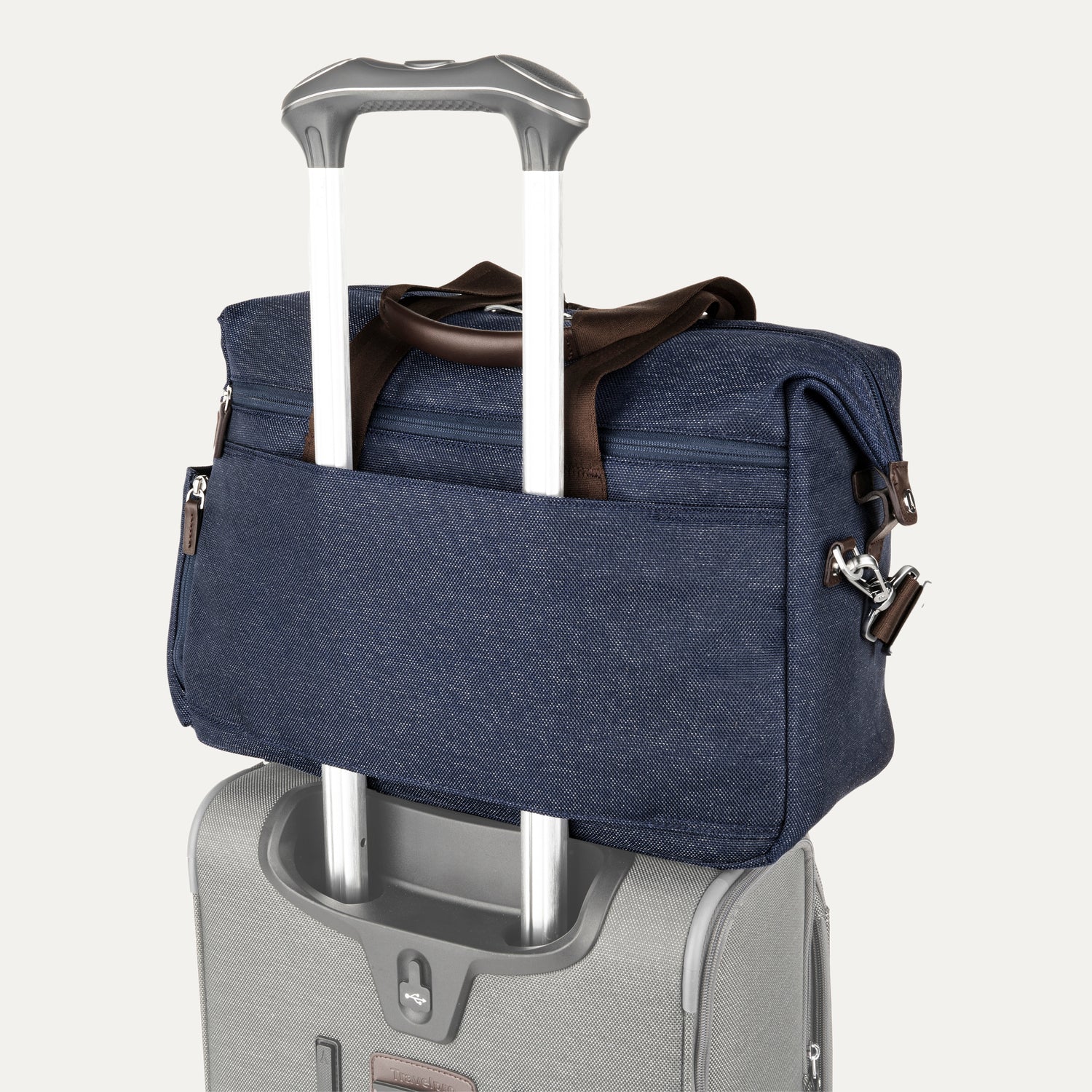 True navy tote secured over suitcase handle using rear strap, on a white background