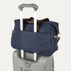 True navy tote secured over suitcase handle using rear strap, on a white background