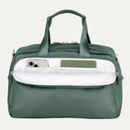 Green travel bag with a white interior pocket showcasing phone and notebook on a light gray background