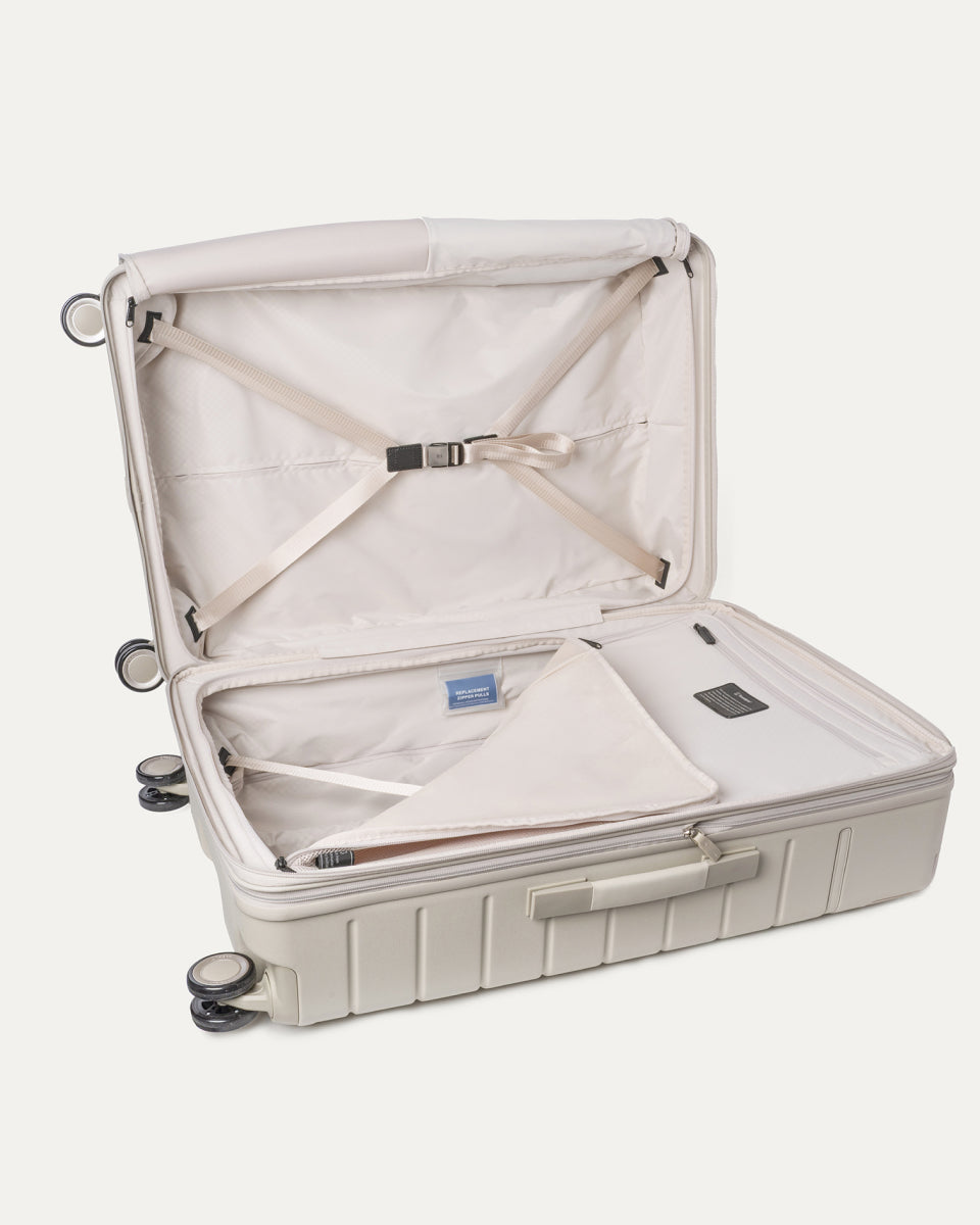 Open interior of the Large Check-In from the Travelpro Platinum Reserve Carry-On / Medium / Large Hardside Set in Sandstone with hold-down straps