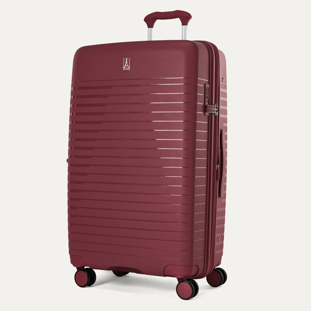 Three-quarter view of the Optima Expandable Large Check-In hardside spinner in Tibetan Red, showcasing the durable textured exterior, telescoping handle, and multi-directional spinner wheels.