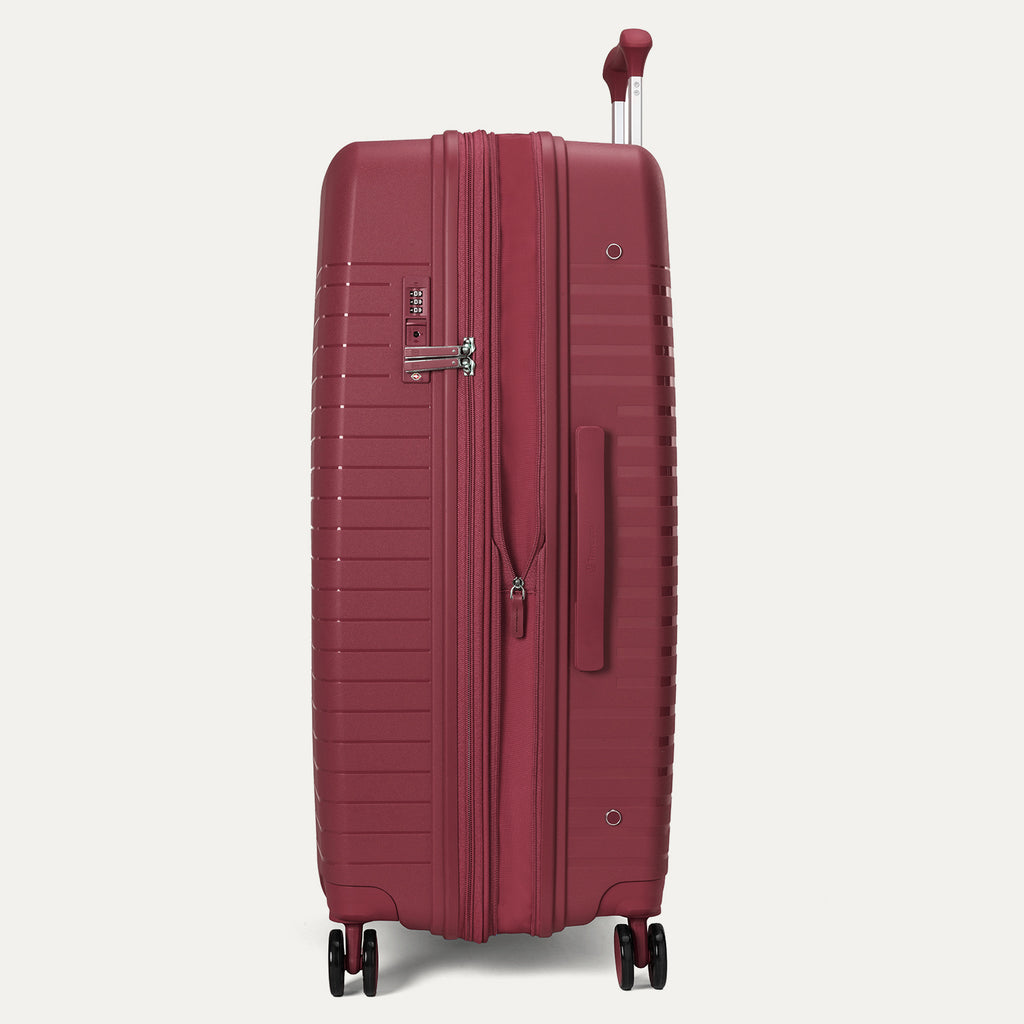 Side-profile view of the Optima Expandable Large Check-In hardside spinner in Tibetan Red, highlighting the side-mounted TSA-approved combination lock, sturdy side carry handle, and smooth-rolling spinner wheel system.