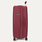 Side-profile view of the Optima Expandable Large Check-In hardside spinner in Tibetan Red, highlighting the side-mounted TSA-approved combination lock, sturdy side carry handle, and smooth-rolling spinner wheel system.
