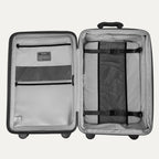 Interior view of the open Optima Expandable Medium Check-In suitcase in Black, showcasing the spacious split-case design with zippered mesh divider panels, compression straps, and interior accessory pockets.