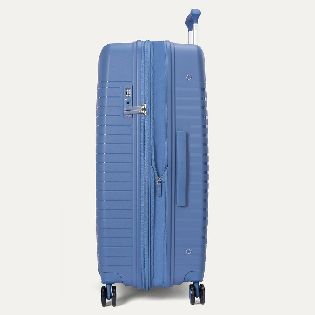 Side-profile view of the Optima Expandable Large Check-In hardside spinner in Horizon Blue, highlighting the expansion zipper, side-mounted TSA-approved combination lock, and sturdy side carry handle.