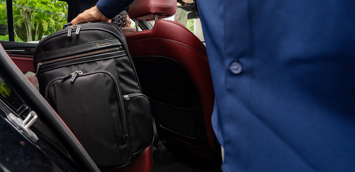 Person placing a black backpack into a car