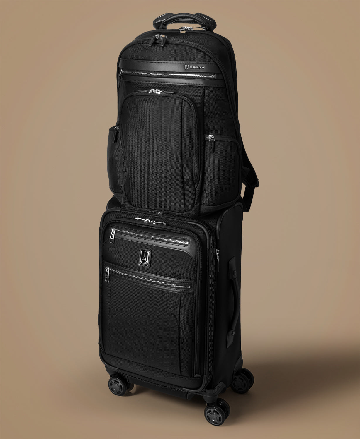 Black suitcase with a smaller black backpack on a beige background