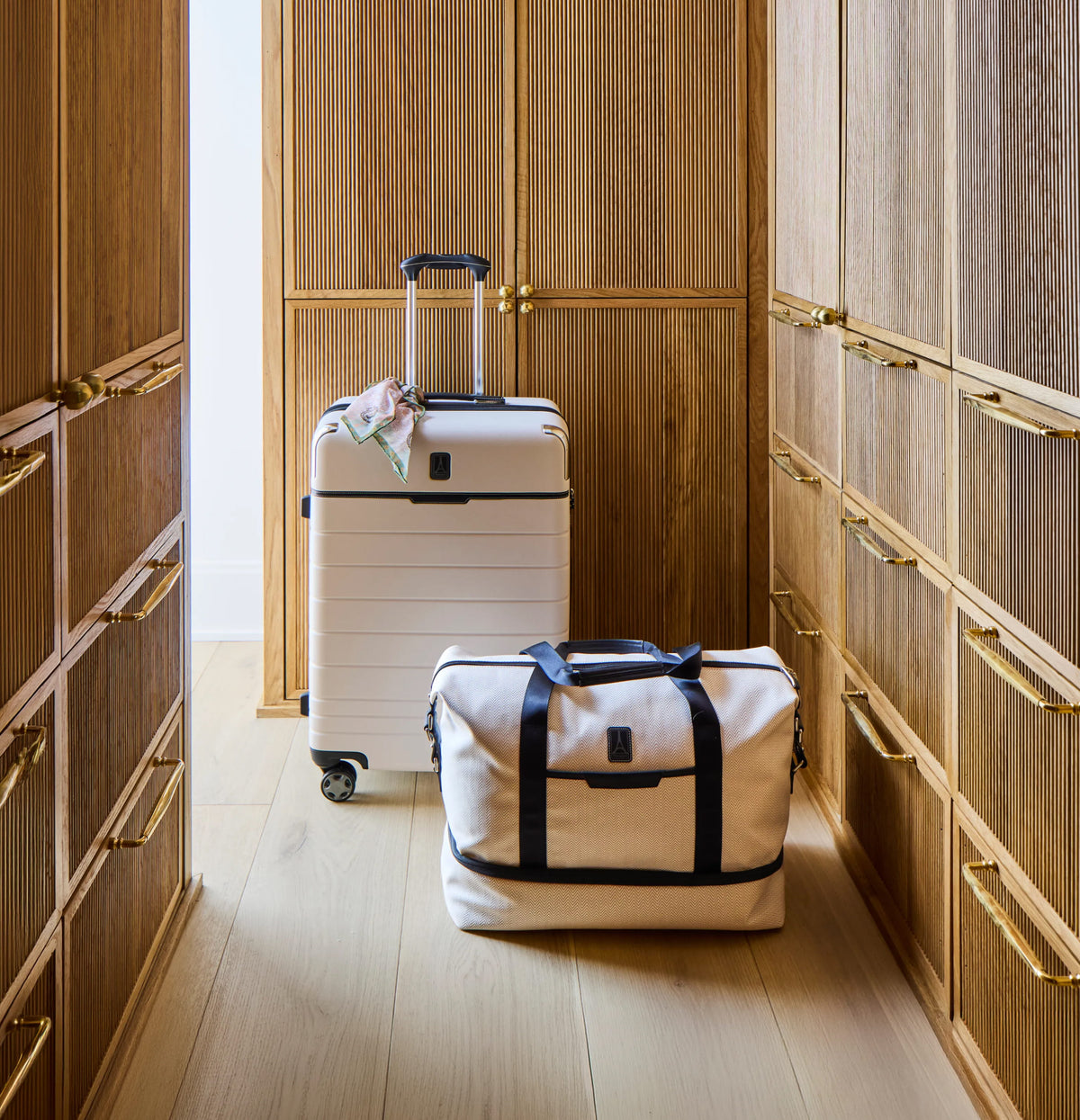 Travelpro x Travel + Leisure suitcase and weekender in White Sand in a wood-paneled closet