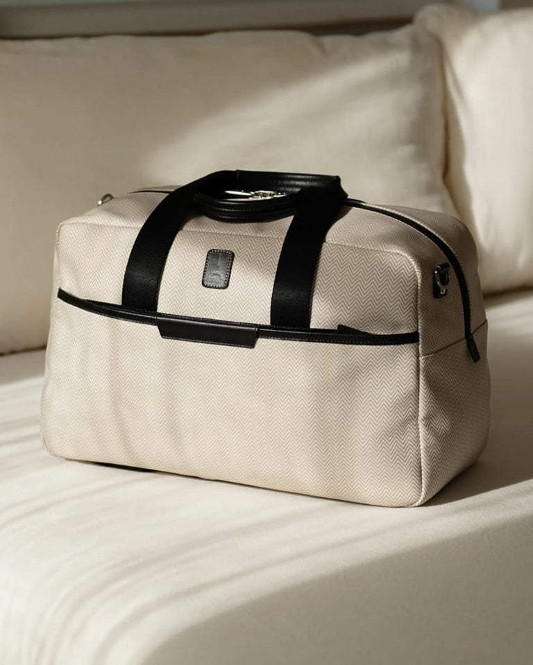 Travelpro x Travel + Leisure UnderSeat Tote in White Sand herringbone on a sofa