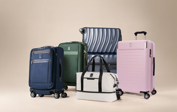 Blue, green, and pink luggage standing with a white duffel bag.