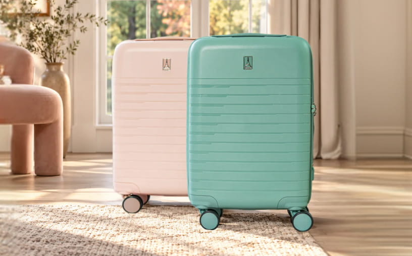 Two hard-shell spinner suitcases standing on a rug in a bright room. The front suitcase is mint green and the rear one is pale blush pink.