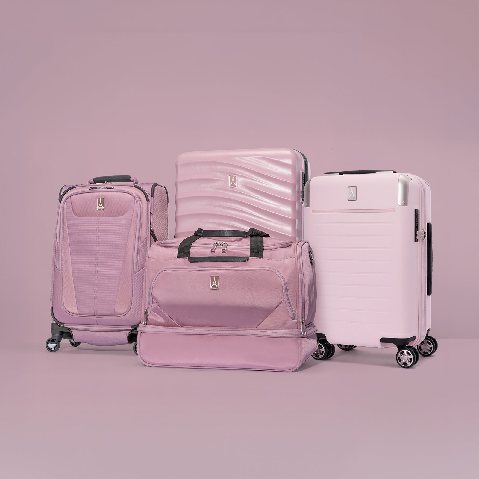 Studio shot featuring a collection of Travelpro pink luggage items, including a soft-sided carry-on on the left, a travel duffel bag in the center foreground, a hardshell medium spinner in the background, and a hardshell carry-on spinner on the right, all set against a muted pink-toned background.