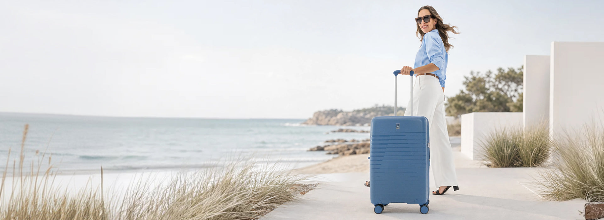 Woman with blue suitcase in front of beach
