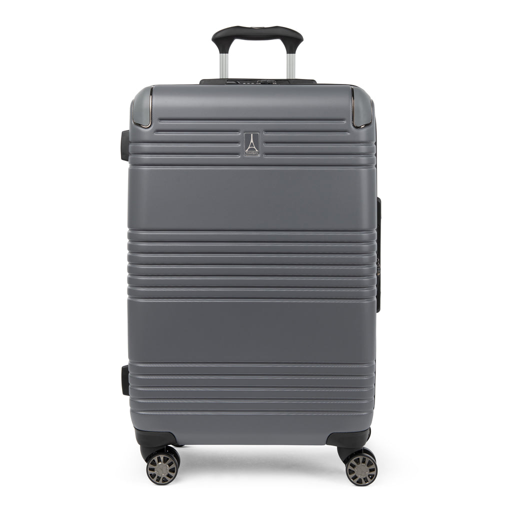 Front view of the Travelpro Roundtrip Medium Check-In Expandable Spinner in Gunmetal Gray, showing textured hardshell design with horizontal ridges, a small metallic logo, and four multi-directional wheels against a clean white background.