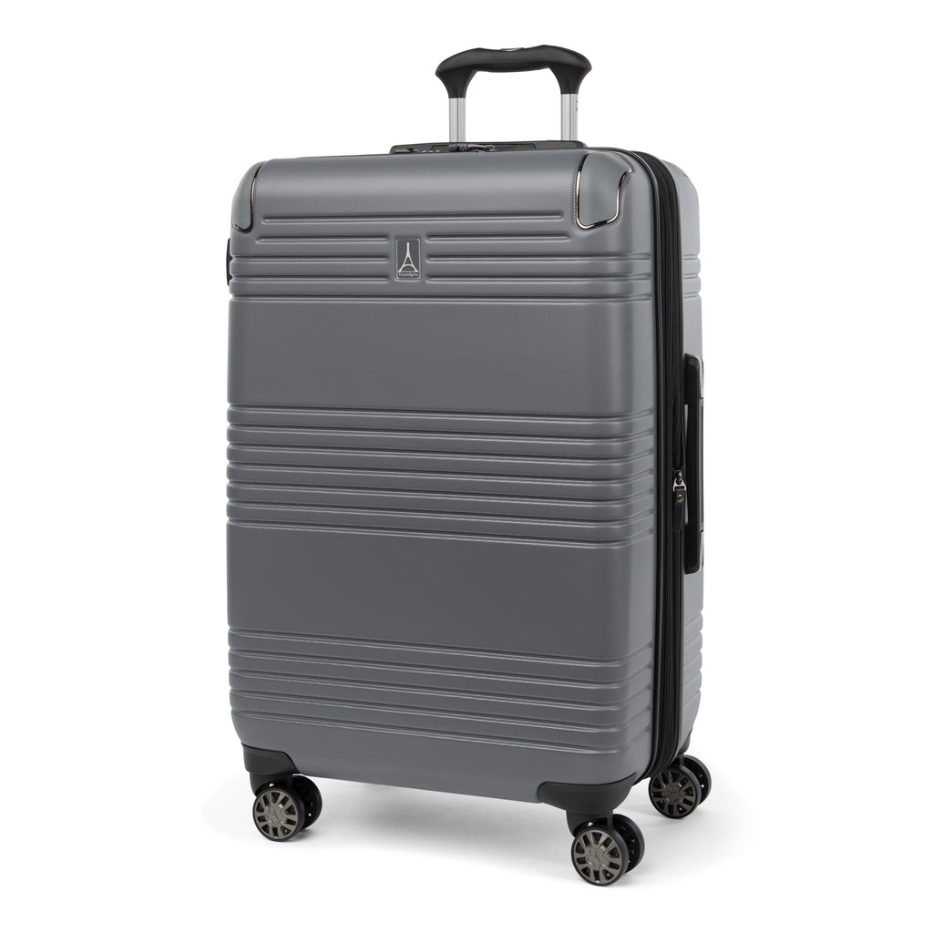 Three-quarter front view of the Travelpro Roundtrip Medium Check-In Expandable Spinner in Gunmetal Gray, showing textured hardshell design with horizontal ridges, a small metallic logo on the front, and four multi-directional wheels against a clean white background.