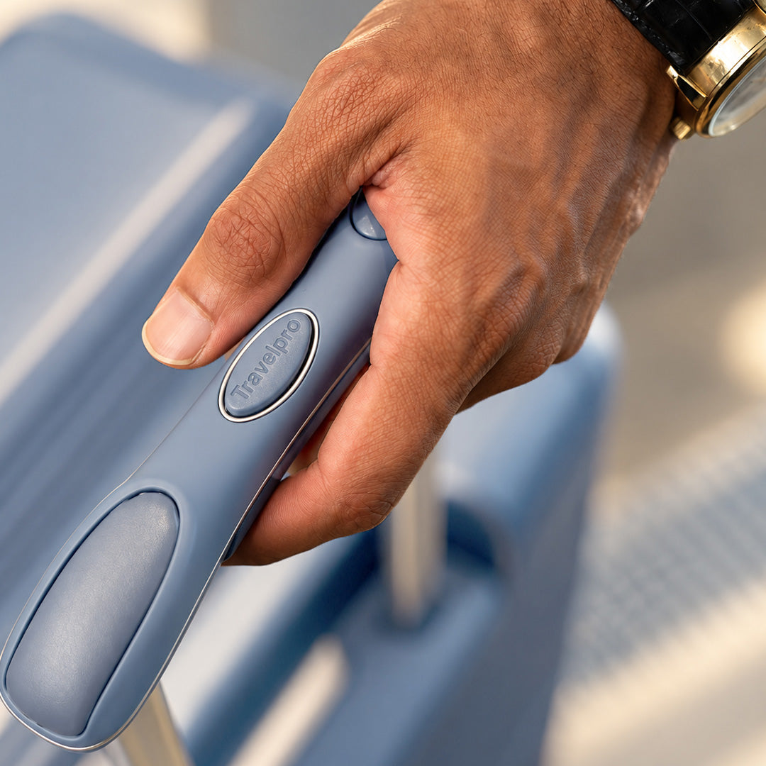 Hand gripping the handle of a Steel Blue Platinum Reserve suitcase