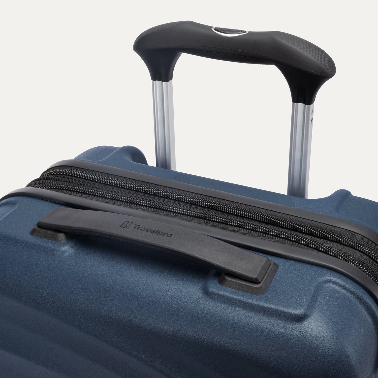 close-up view of the top of the midnight blue travelpro maxlite® air v2 hardside spinner, showing the cushioned rubberized contour grip carry handle and the adjustable powerscope lite extension handle with a push-button release.