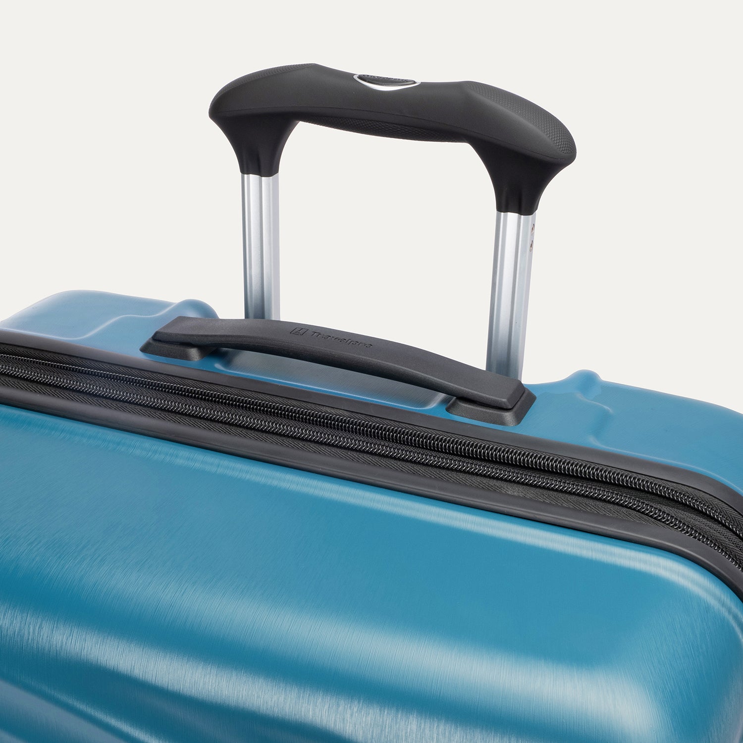 close-up view of the teal travelpro maxlite® air v2 hardside spinner, showing the cushioned top carry handle with the travelpro logo and the rubberized contour grip on the powerscope lite extension handle.