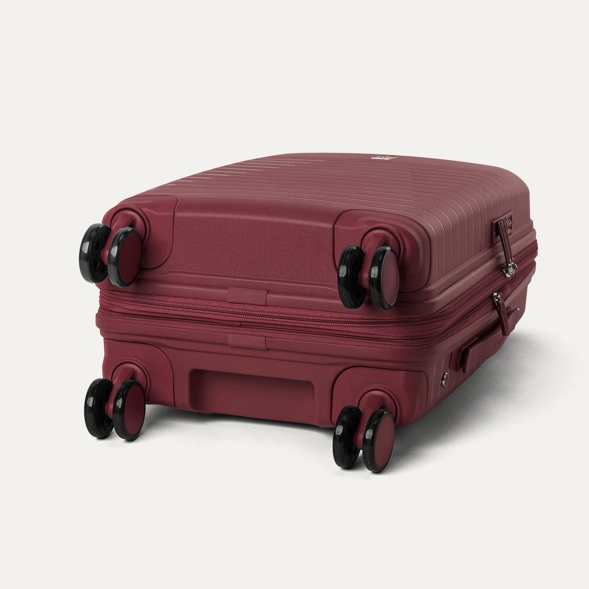 bottom view of the tibetan red travelpro optima® expandable carry-on hardside spinner, showing the four 360-degree self-aligning spinner wheels and the protective polypropylene base.
