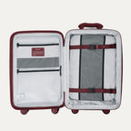 interior view of the open tibetan red travelpro optima® hardside carry-on, showing the organized packing system with a zippered divider panel, mesh pockets, and red compression straps over the main compartment.