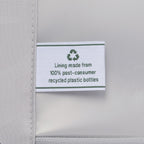 close-up view of the interior lining of the tibetan red travelpro optima® hardside carry-on, showing a white fabric label with a green recycling symbol that reads , lining made from 100% post-consumer recycled plastic bottles.