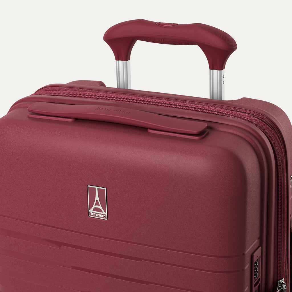 close-up view of the top of the tibetan red travelpro optima® hardside carry-on, showing the color-matched cushioned carry handle, the travelpro logo badge on the shell, and the powerscope lite extension handle.