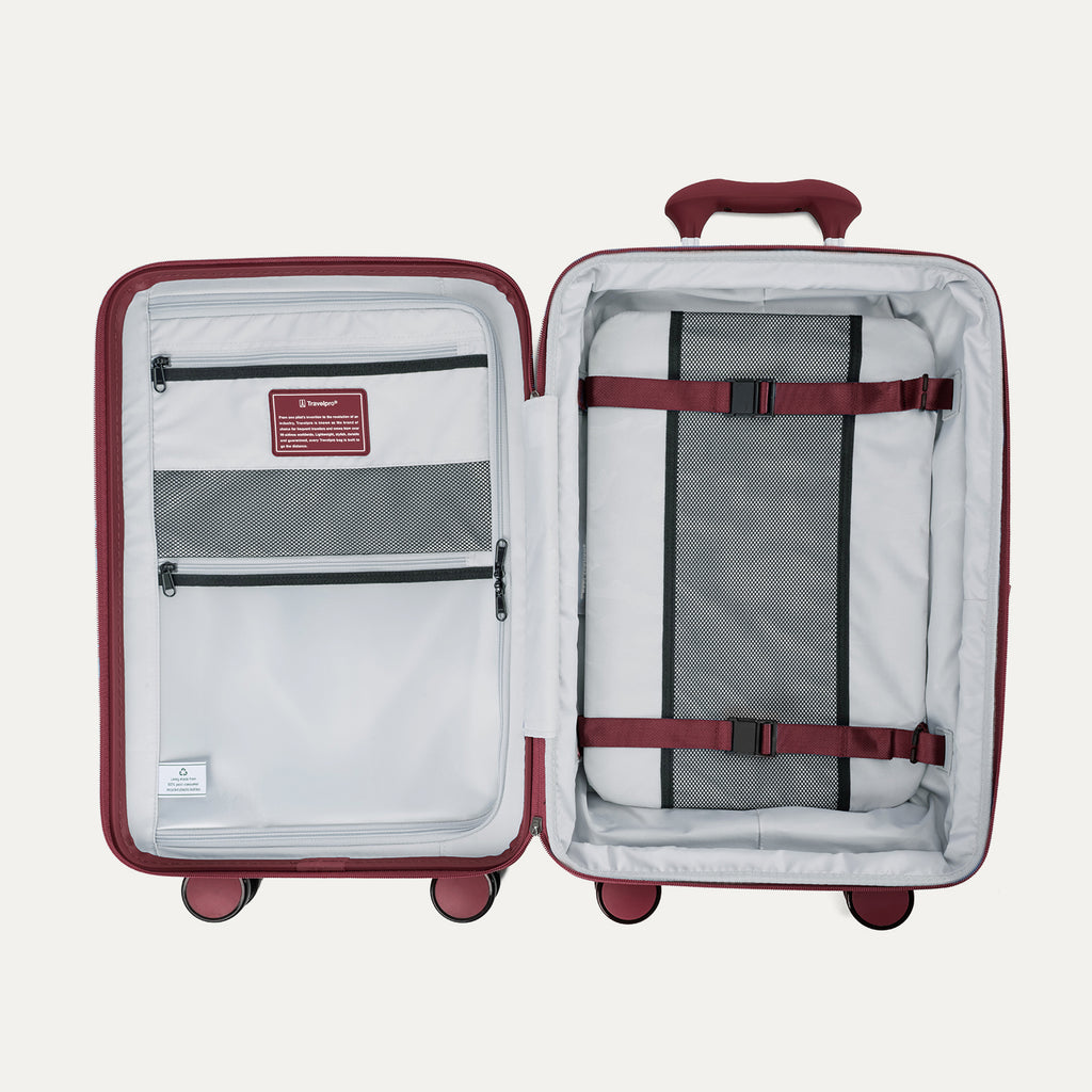 interior view of the open tibetan red travelpro optima® expandable compact carry-on hardside luggage, showing the organized packing system with a zippered divider panel, mesh pockets, and red compression straps over the main compartment.