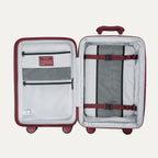 interior view of the open tibetan red travelpro optima® expandable compact carry-on hardside luggage, showing the organized packing system with a zippered divider panel, mesh pockets, and red compression straps over the main compartment.