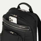 close-up view of the black travelpro platinum elite business laptop backpack 27l, showing a white smartphone being placed into the quickslip front pocket with magnetic closure for easy access.