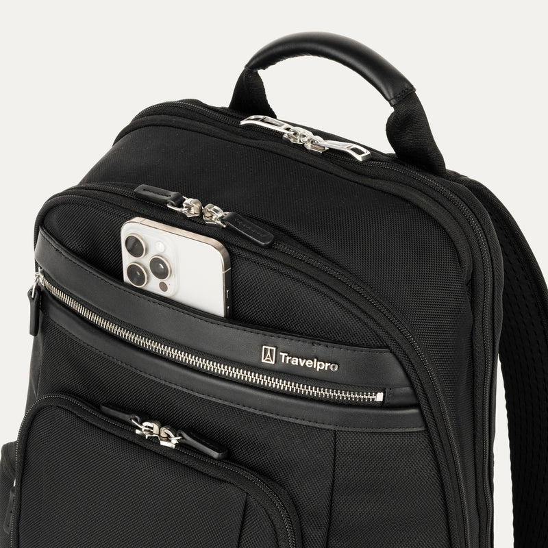 close-up view of the black travelpro platinum elite business laptop backpack 27l, showing a white smartphone being placed into the quickslip front pocket with magnetic closure for easy access.