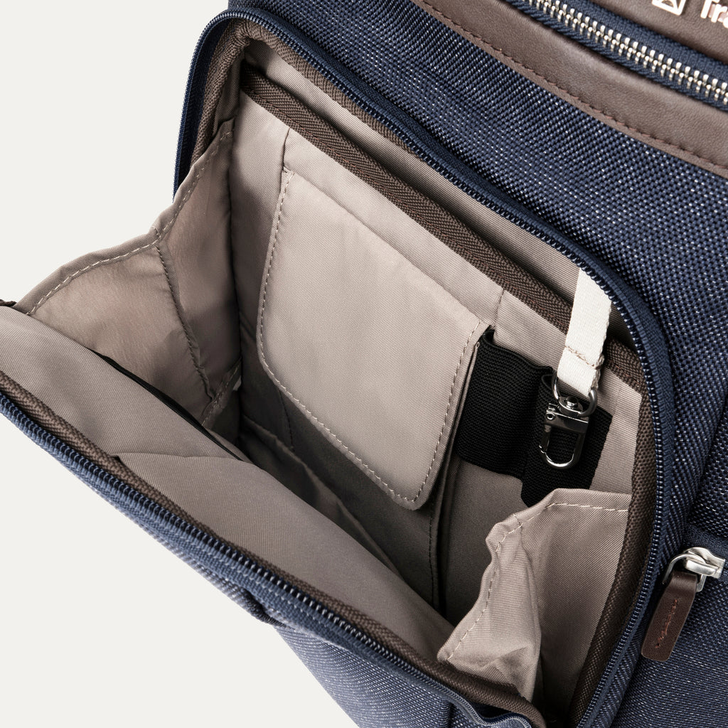 interior view of the front organizational compartment of the true navy travelpro platinum elite business laptop backpack 27l, showing built-in pockets for pens, a key tether, and a small zippered security pocket against a light-colored lining.