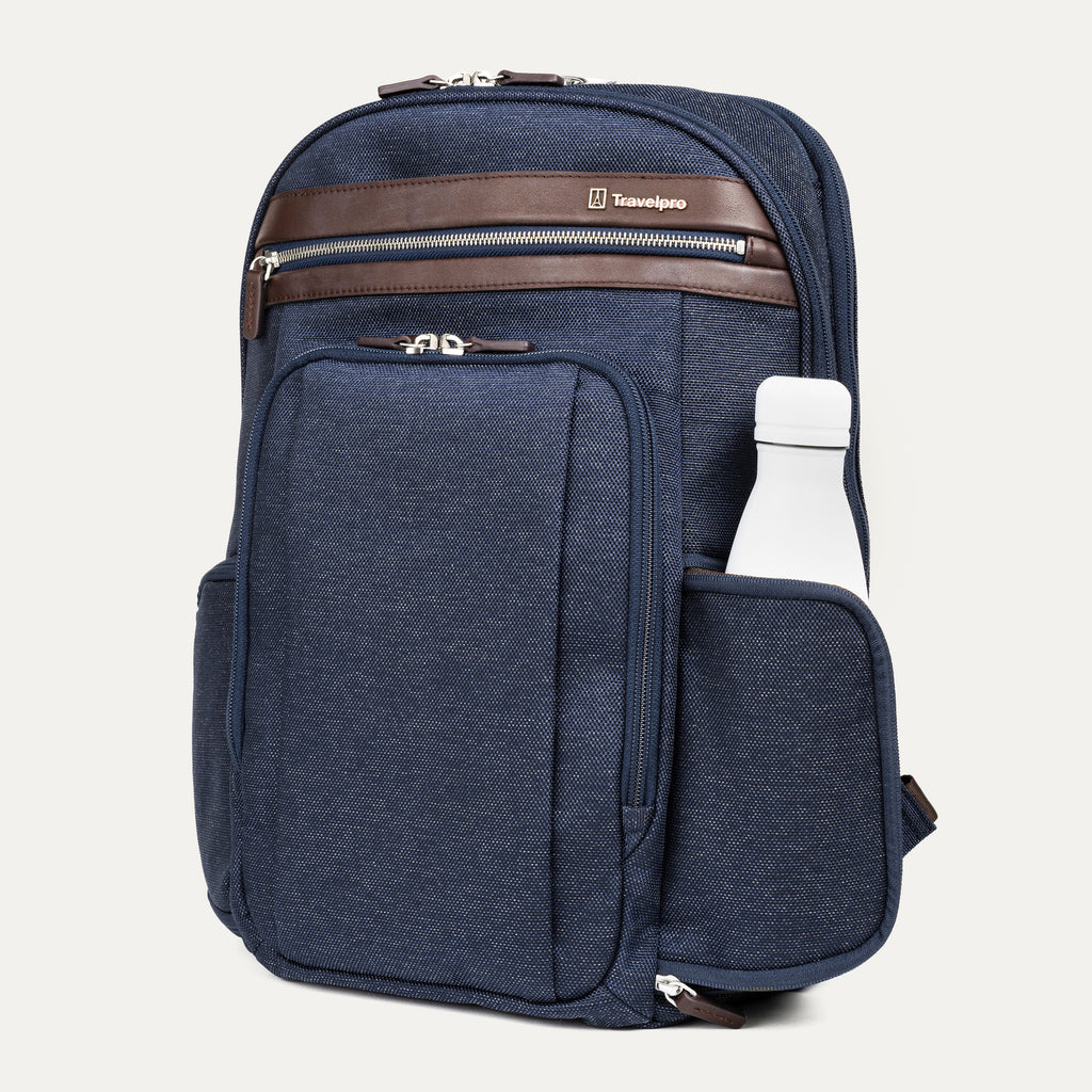 side view of the true navy travelpro platinum elite business laptop backpack 27l, showing a white reusable water bottle tucked into the side pocket with dark brown leather trim.