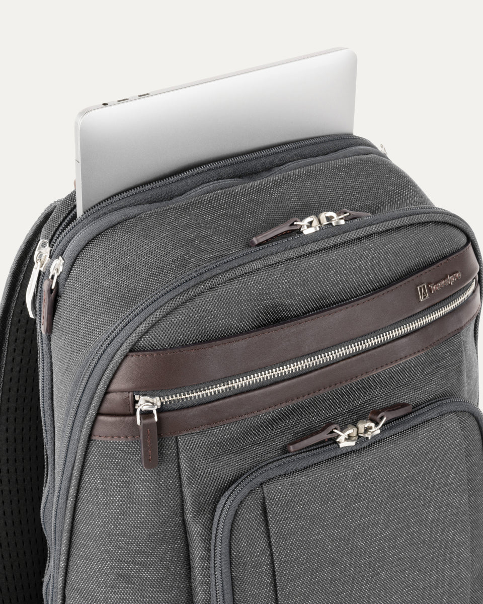close-up view of the vintage grey travelpro platinum elite business laptop backpack 27l, showing a silver laptop being tucked into the dedicated padded electronics sleeve with dark brown leather trim.