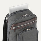 close-up view of the vintage grey travelpro platinum elite business laptop backpack 27l, showing a silver laptop being tucked into the dedicated padded electronics sleeve with dark brown leather trim.
