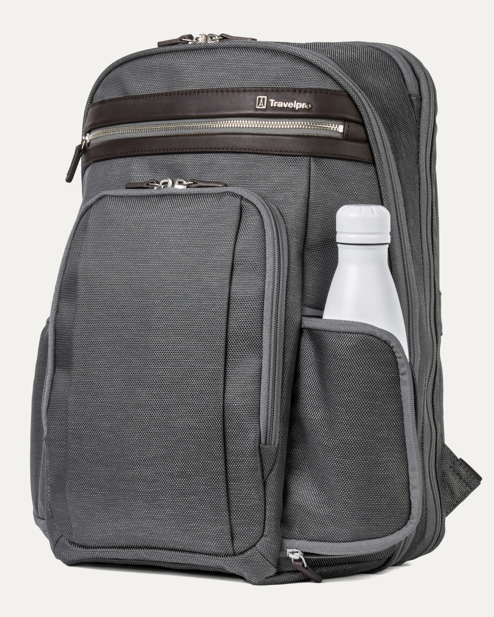 side view of the vintage grey travelpro platinum elite business laptop backpack 27l, showing a white reusable water bottle tucked into the integrated side pocket with dark brown leather trim.