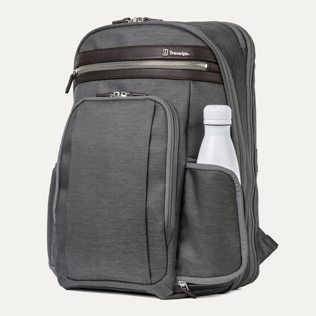 side view of the vintage grey travelpro platinum elite business laptop backpack 27l, showing a white reusable water bottle tucked into the integrated side pocket with dark brown leather trim.