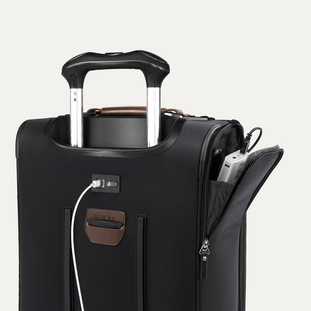 close-up of the shadow black travelpro platinum elite compact carry-on featuring a white usb cable plugged into the external charging port and a power bank stored in the dedicated exterior battery pocket.
