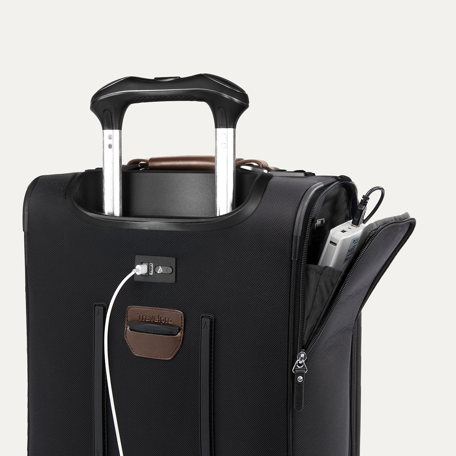 close-up of the shadow black travelpro platinum elite compact carry-on featuring a white usb cable plugged into the external charging port and a power bank stored in the dedicated exterior battery pocket.