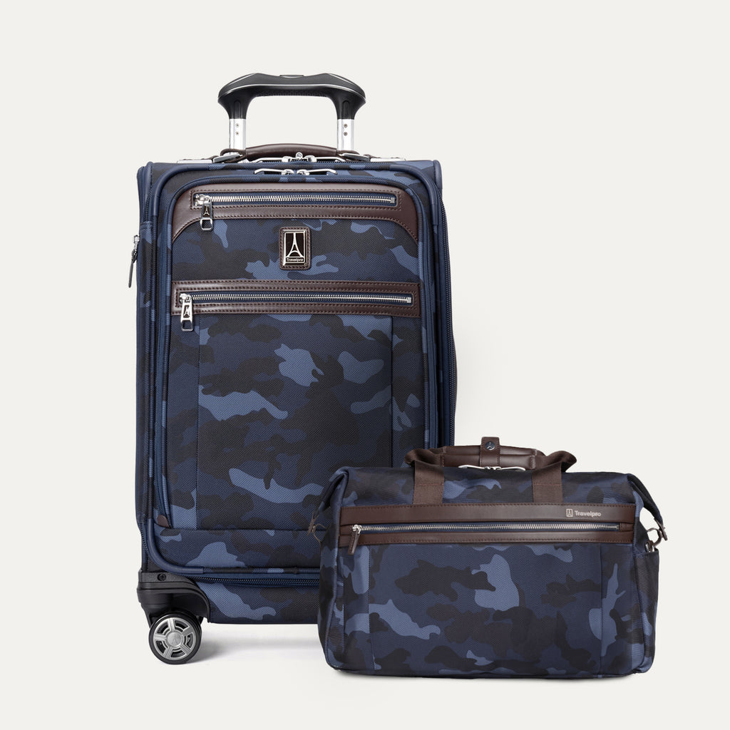 a 2-piece travel luggage set in navy blue camouflage featuring the travelpro platinum elite 21-inch carry-on spinner and the matching underseat tote bag, shown with premium brown leather accents and chrome hardware.