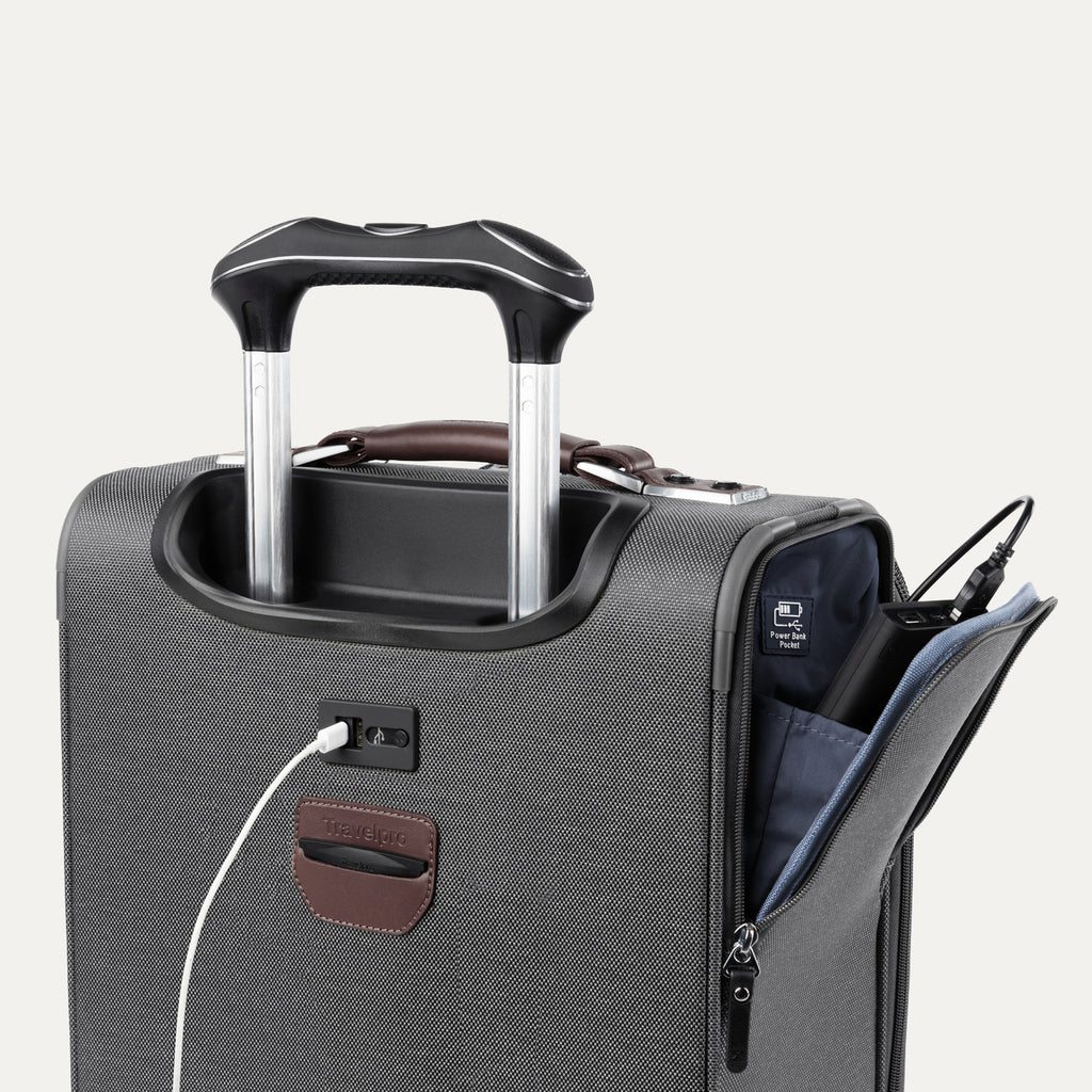detail view of the vintage grey travelpro platinum elite carry-on spinner tote showing the external usb charging port with a cable plugged in, and the side pocket open to reveal the power bank pocket label and stored battery.