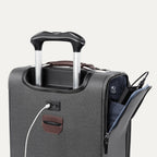 detail view of the vintage grey travelpro platinum elite carry-on spinner tote showing the external usb charging port with a cable plugged in, and the side pocket open to reveal the power bank pocket label and stored battery.