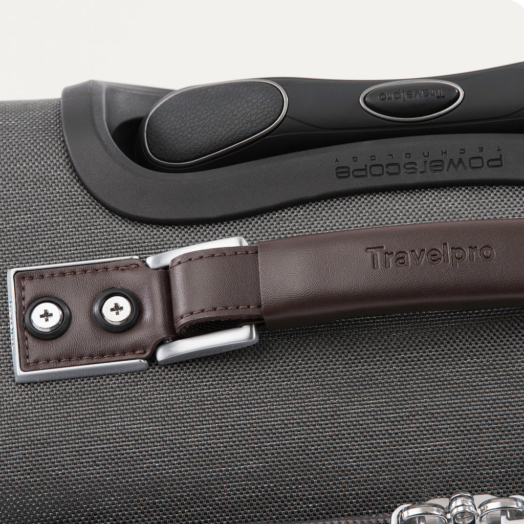 close-up top view of the vintage grey travelpro platinum® elite carry-on spinner tote, showing the brown leather top carry handle with silver-tone hardware, the embossed travelpro logo, and the contour grip on the powerscope extension handle.