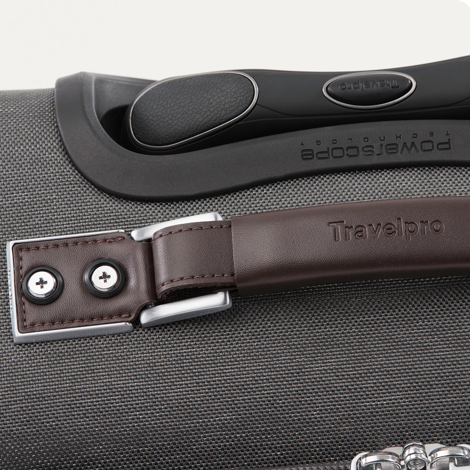 close-up top view of the vintage grey travelpro platinum® elite carry-on spinner tote, showing the brown leather top carry handle with silver-tone hardware, the embossed travelpro logo, and the contour grip on the powerscope extension handle.
