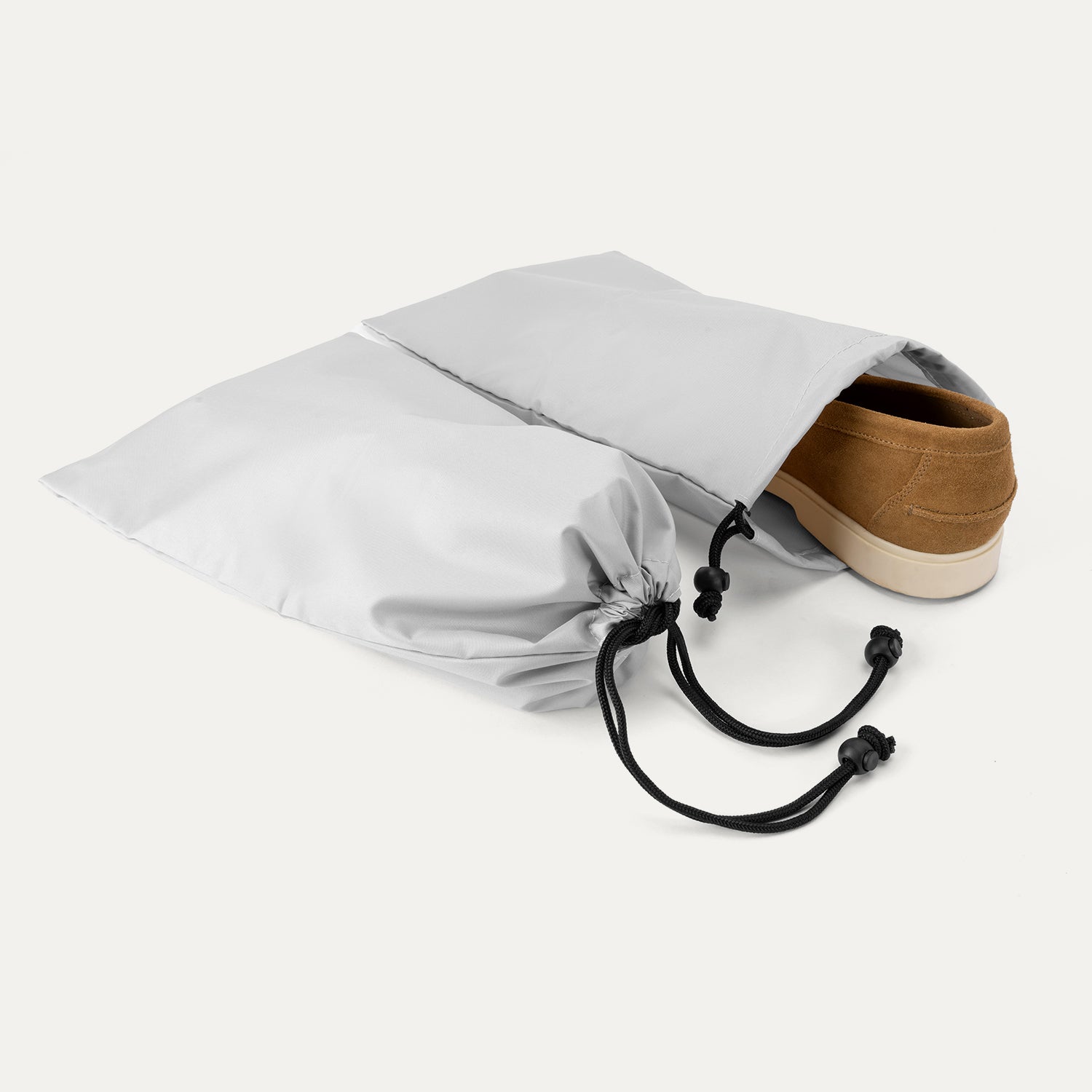 detail view of the two removable gray shoe bags included with the travelpro platinum elite compact carry-on hardside spinner in aviator navy, shown with a brown suede loafer being tucked inside for organized packing.