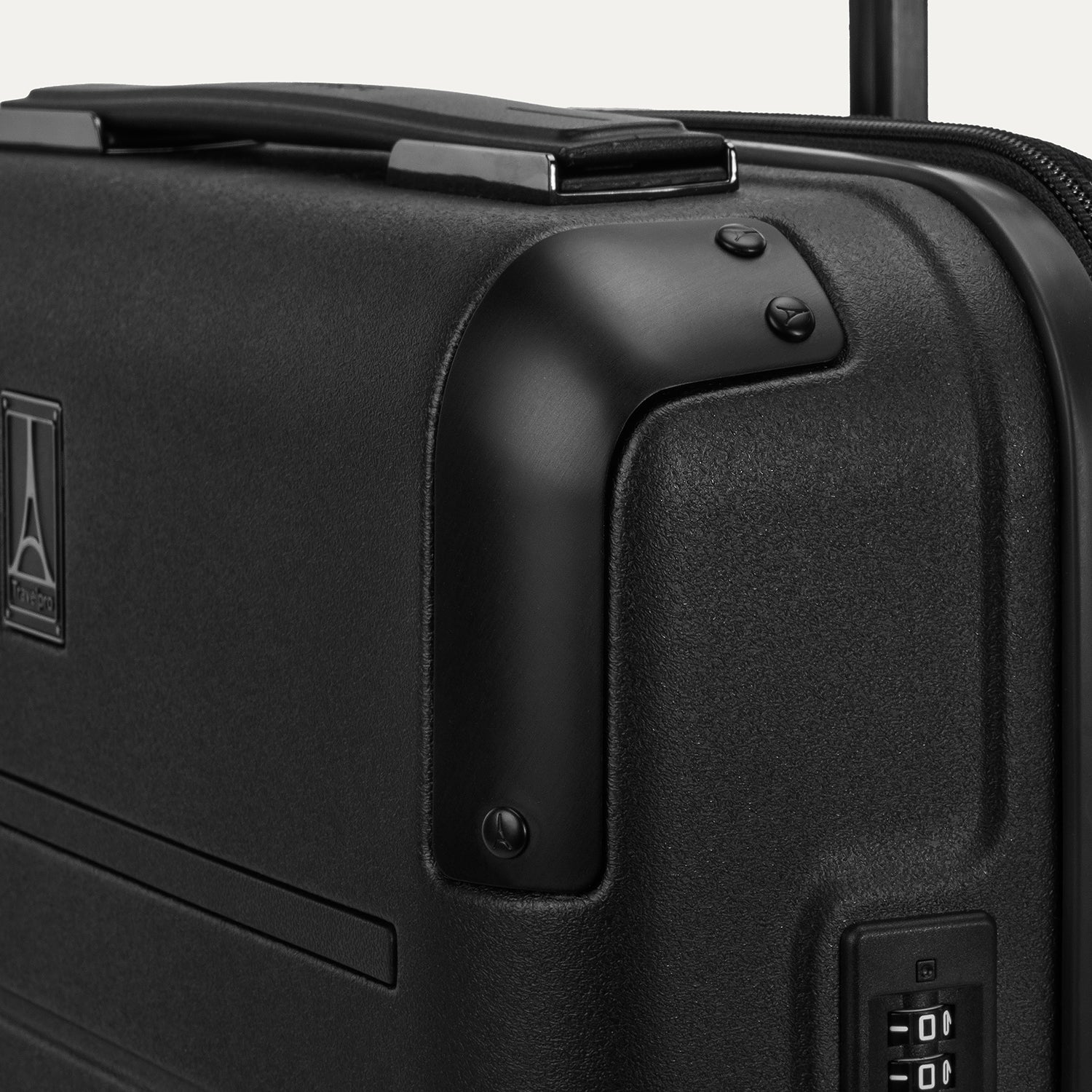 Close-up detail of the Travelpro Platinum Elite Compact Carry-On Hardside Spinner in Shadow Black, highlighting the polished aluminum corner armor and the integrated TSA-approved combination lock.